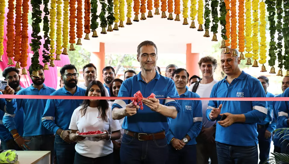 Guillaume Dourdin cutting the red ribbon surrounded by Veolia staff under a arch of traditional marigold garlands.