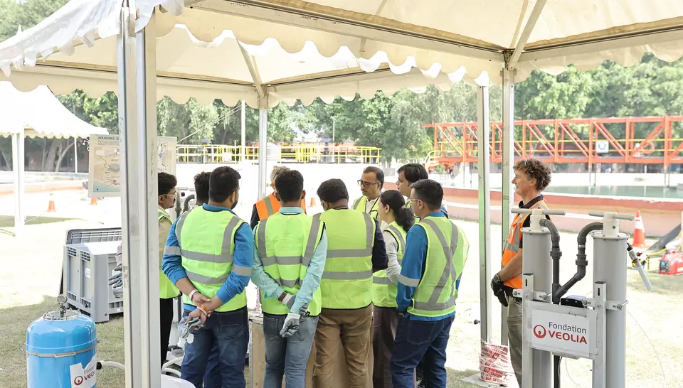 Trainees in high-visibility vests gathered under a tent in front of a Veolia Foundation mobile water treatment unit