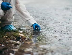 Scientist in protective suite taking water samples from the river / Photo © hedgehog94/Adobe Stock