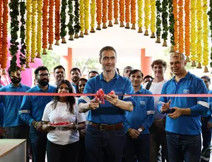 Guillaume Dourdin cutting the red ribbon surrounded by Veolia staff under a arch of traditional marigold garlands.